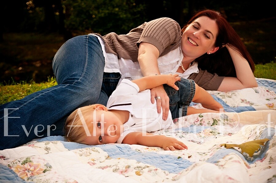 Mother and child lying on floral quilt outside