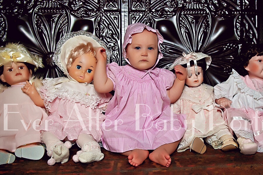 Baby dressed up in doll outfit.