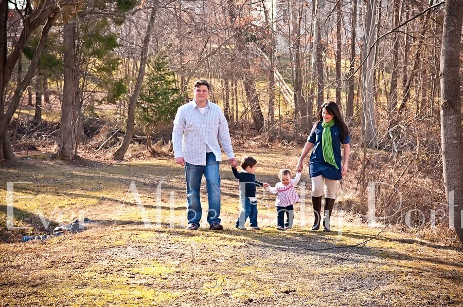 Parents with small children stroll in woods.